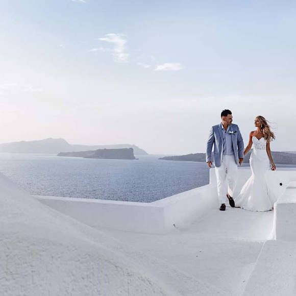 Newlywed couple walking on white rooftop terraces with ocean views at Grand Ambassador hotel